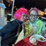 woman in red wig and man sticking tongue out in costume