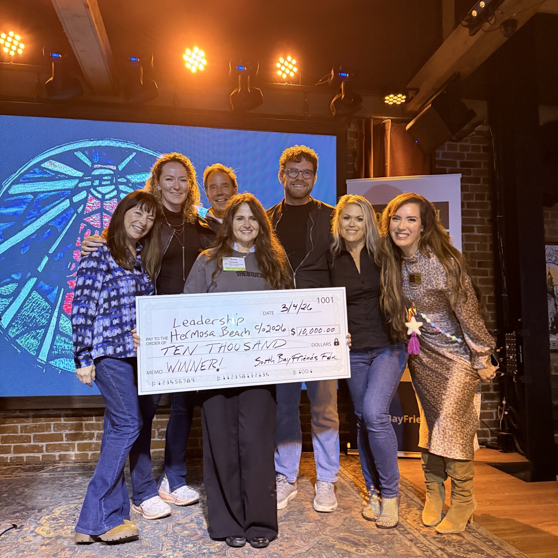 group of people on stage wtih a big check